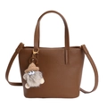 Brown lychee-texture bucket bag with a cute plush monster pendant on white background - Tea Brown