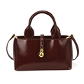 Detail of burgundy patent leather bucket bag with gold gourd charm and pleated texture - Burgundy