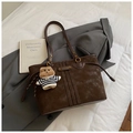 Detail of dark brown tote bag with stitching, gold hardware, and a plush bear charm - With Pendant / Brown