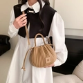 Sac à bandoulière plissé camel avec logo D porté par un mannequin en tenue chic - Kaki