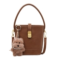 Deep brown matte leather bucket bag with top handle and plush dog charm on white background - With Pendant / Brown