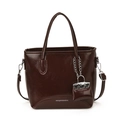 Dark brown shiny bucket bag with dual handles and a mini charm pendant on the side - Brown