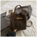Dark brown suede bucket bag with gold clasp and crossbody strap in a fashion scene - Brown