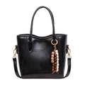 Elegant black glossy bucket bag with ethnic beaded charm and versatile crossbody strap - Black