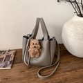 Detail der grauen Lederbeuteltasche mit Plüsch-Hundeanhänger auf einem Holztisch - Mit Anhänger / Grau