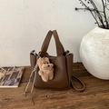 Detail der dunkelbraunen Eimer-Tasche aus Leder mit Plüschbär-Anhänger und Logo - Mit Anhänger / Braun