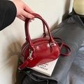 Bolso Boston de cuero brillante burdeos con asas cortas y correa ajustable en entorno real - Talla única / Burdeos