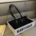 Detalle de bolso baguette de ante negro con hebilla en una caja de regalo premium - Negro