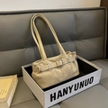Detalle de bolso hobo de ante beige con hebillas metálicas en una caja de regalo blanca - Caqui
