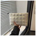 Borsa cosmetica trapuntata argento con finitura metallica e cerniera, tenuta in mano - Bianco