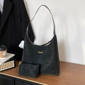 Bolso tote retro de ante negro con pequeño neceser frente a una pared de fondo blanco - Negro