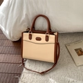 Sac fourre-tout rétro bicolore beige et marron avec bandoulière sur un tapis doux - Kaki