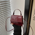 Detalle del bolso cuadrado de charol rojo vino con acabado brillante y asa superior - Burdeos