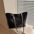 Bolso tote negro minimalista de cuero para mujer sobre una bufanda gris con luz suave - Negro