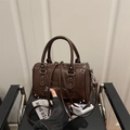 Dark brown Boston bag with silver rivets and dual handles in a lifestyle setting - Coffee