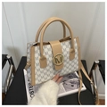 Detail of printed handbag showing gold M-logo buckle and beige leather strap accents - White