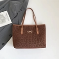 Brown leopard print tote bag with golden bow and leather handles on grey blazer - Brown
