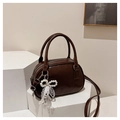 Detail of dark brown leather handbag featuring a white pearl bow and lace charm - With Pendant Style / Coffee