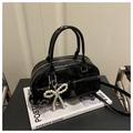 Detail of black patent leather Boston bag with double handles and a pearl bow charm - Black