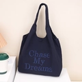 Detail of navy nylon tote bag with blue Chase My Dreams embroidery in a cozy home setting - Dark Blue