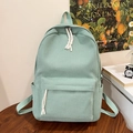 Detalle de mochila de pana verde claro con cremalleras y bolsillos laterales en escritorio - Verde