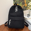 Detalle de mochila de pana negra con tirador de cuerda blanca y decoración escolar - Negro