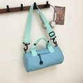 Light blue cylinder sports duffel bag with mint green straps on a wooden hook - Blue