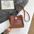 Brown woven bucket bag with wood buckle and thin leather strap in a chic setting - Brown