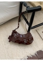 Detail van donkerbruine lakleren hobo-tas met zilveren ogen en een beren-bedeltje - koffiekleur