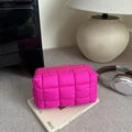 Neonpinke gesteppte Kosmetiktasche mit Puffer-Textur auf einem Magazin für den Alltag - Rosenrosa