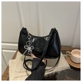 Detalle del bolso media luna de charol negro con colgante de lazo de perlas y corazón - Negro