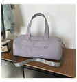 Detail of lavender nylon travel bag with wide gray strap on a dark wooden surface - Gray