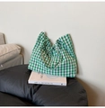 Detail of green and white gingham tote bag with tie-up closure on a casual leather seat - Green