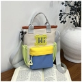 Detail of color-block canvas crossbody bag with multi-pockets on a wooden desk - Yellow and Green