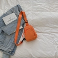 Minimalist bright orange nylon sling bag with adjustable strap over a denim jacket - Orange