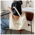 Détail d'un cabas blanc brillant avec texte vert Skillfully dans une scène de mode - Blanc