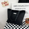Minimalist black canvas tote bag with Believe In Yourself patch in a casual setting - Black
