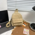 Detail of beige corduroy mini backpack with flap front pocket on a clean desk - Khaki