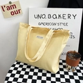 Minimalist light yellow canvas tote bag with a durable handle and fabric label patch - Yellow