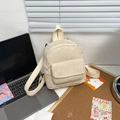 Close-up of a mini cream corduroy backpack with a front flap pocket on a desk setup - Beige