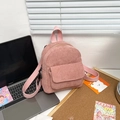 Pink corduroy mini backpack detail showing textured fabric and front pocket on desk - Pink