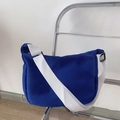 Detail view of Klein blue nylon crossbody bag with wide white adjustable strap on a chair - With Badges / Blue