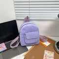 Detailed macro view of purple corduroy fabric texture and front flap pocket on a mini backpack - Purple
