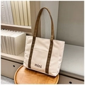 Detalle de un bolso tote minimalista de lona blanco roto con asas marrones y mini - Caqui