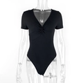 Detail of black ribbed bodysuit featuring a deep V-neck and twist front design - S / Black