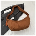 Detail shot of caramel nylon crescent bag with quilted shoulder strap on grey blazer - Brown