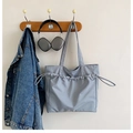 Detalle de bolso tote gris azulado claro con textura de cordón colgado de un soporte - Azul