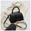 Minimalistische schwarze Handtasche aus Leder mit goldener Hardware auf weißem Blazer - Schwarz