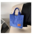 Bolso tote minimalista de pana azul marino con parche de cuero en un sofá beige - Azul