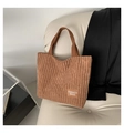 Elegante bolso tote de pana marrón con parche de moda sobre un sofá de cuero - Marrón